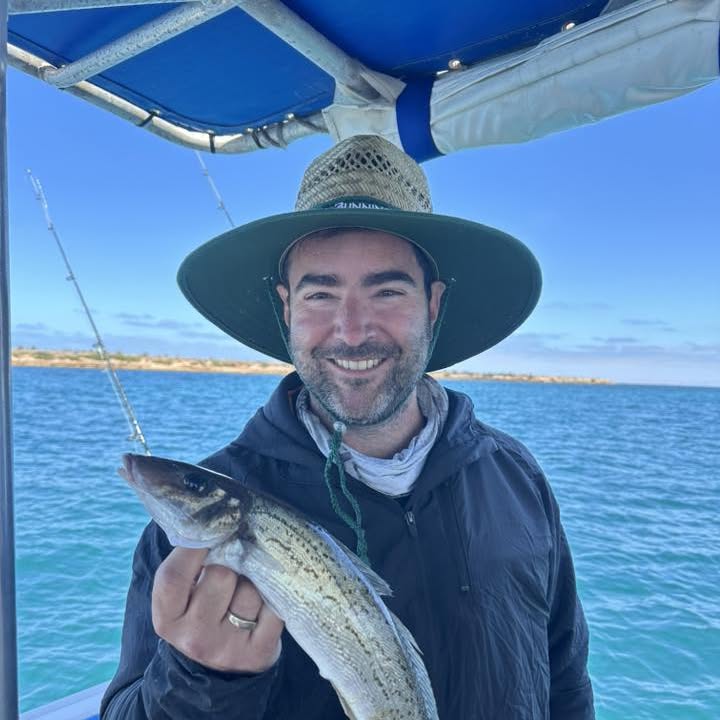 An angler in a hat holding a King George Whiting