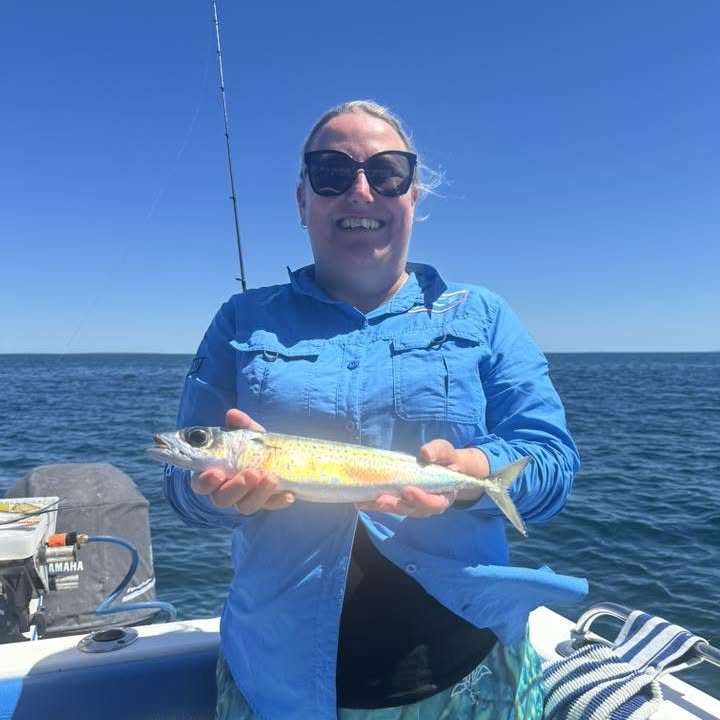 A guest smiling with her catch on a clear day