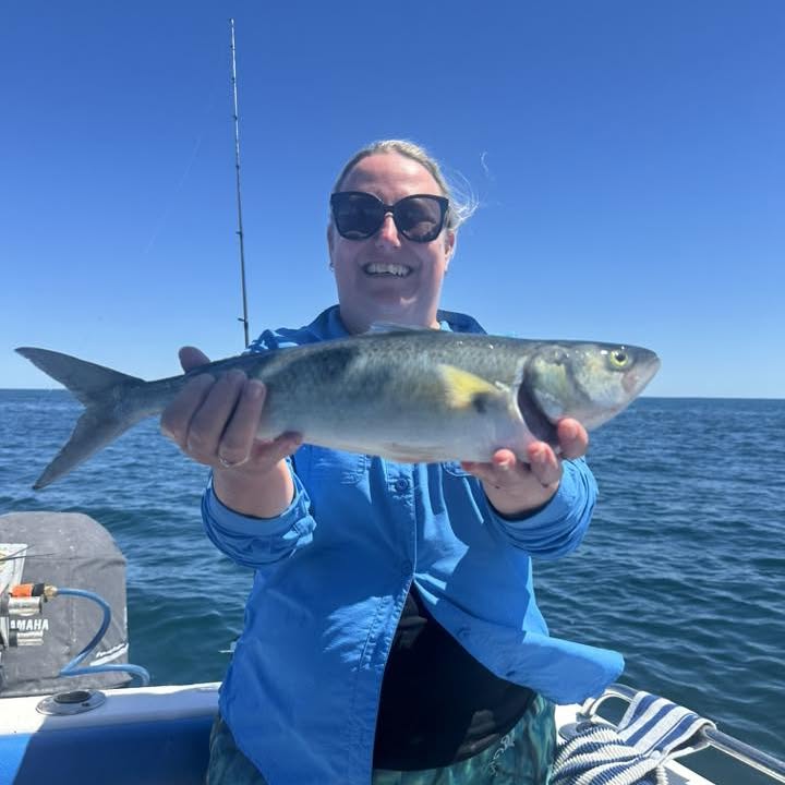 A guest holding up her catch on a bright blue day