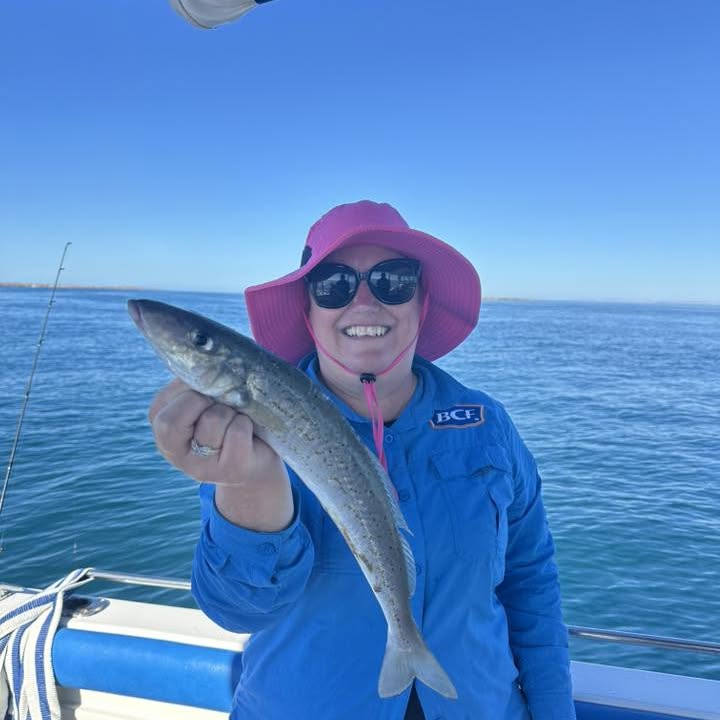 A guest in a pink hat holding up a whiting